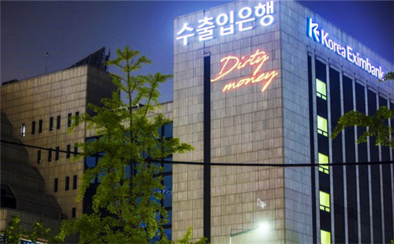 Greenpeace Korea shines a laser light on the headquarters building of the Export-Import Bank of Korea (Eximbank) in Seoul on Sunday, displaying messages that read, ‘Dirty Money’, to call on Eximbank to boycott coal finance. GREENPEACE/THE KOREA HERALD