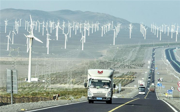 Vehicles pass a wind power farm in Turpan, the Xinjiang Uygur autonomous region. [Photo/Xinhua]