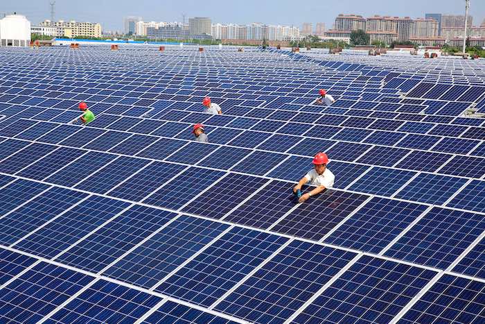 Workers install solar panels on the rooftop of a textile factory in Nantong, China. Credit: Imaginechina Limited / Alamy Stock Photo.