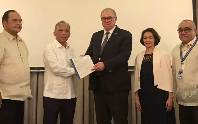Chudakov (centre) presents Cusi with the INIR mission's final report (Image: Philippines DOE)
