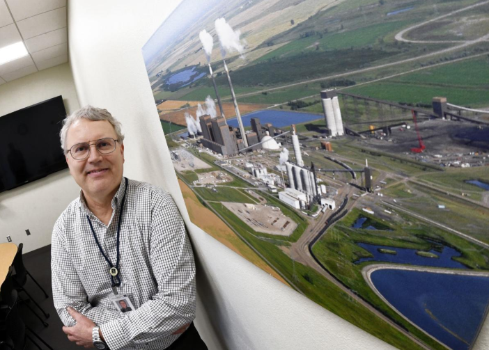 John Bauer, director of North Dakota generation at Great River Energy, stands by a photograph of Blue Flint Ethanol and Great River Energy's Coal Creek Station. The two entities are collaborating on a carbon capture storage project.