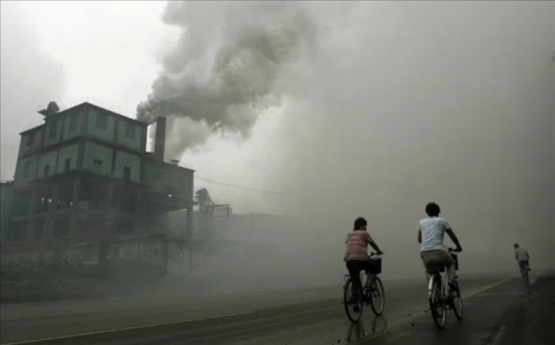 This picture taken July 18, 2006, shows cyclists passing through thick pollution from a factory in Yutian, 100km east of Beijing in China's northwest Hebei province. PETER PARKS/AFP/GETTY IMAGES