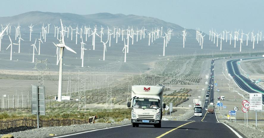 Vehicles pass by a wind farm in Xinjiang Uygur autonomous region. 