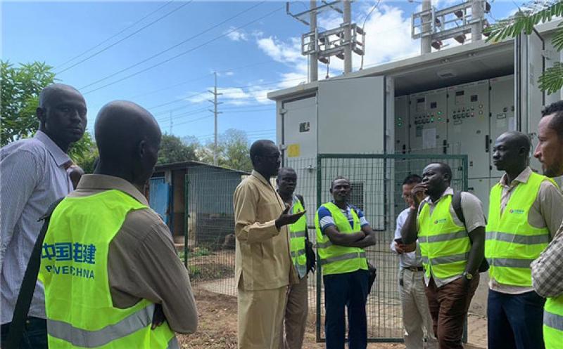 Jacob M. Deng, in a khaki suit, talks with utility workers during the commissioning of a substation in Juba, South Sudan.