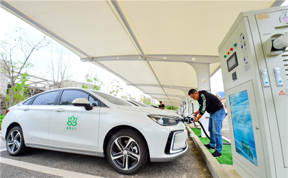 An employee charges new energy vehicles at a charging station in Ganzhou, Jiangxi province. [Photo by Zhu Haipeng/for China Daily]