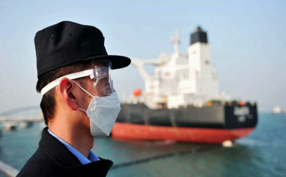 A police officer wearing a mask amid concerns over the COVID-19 coronavirus while keeping watch as a Kuwaiti oil tanker unloads crude oil at the port in Qingdao, in China's eastern Shandong province.