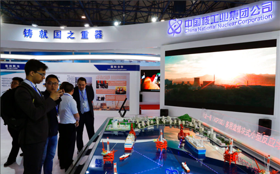 FILE - Staff members from the China National Nuclear Corporation look at models of oil tanker-shaped floating nuclear reactors and oil rigs showcased at the display booth of China's state-owned CNNC, in Beijing, April 27, 2017.