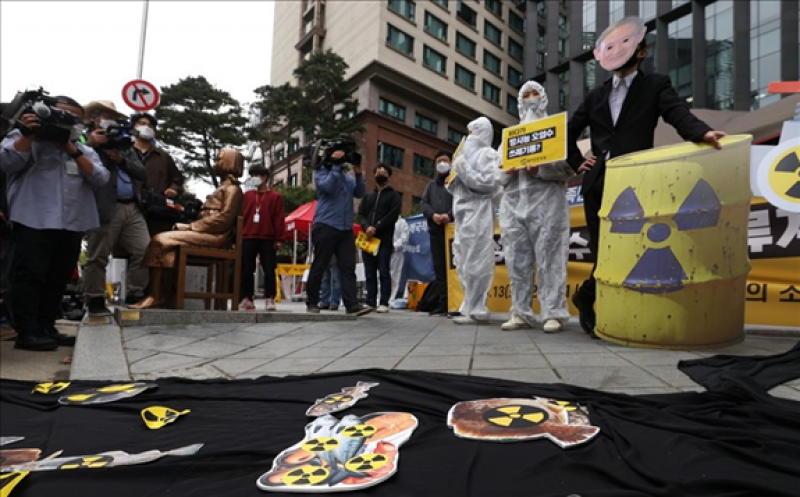 A protestor wearing a mask depicting Japanese Prime Minister Yoshihide Suga simulates the disposal of radioactive water into the ocean during a rally in front of the Japanese Embassy in Seoul on April 13, 2021, as environmental activists express their objection to the Japanese government's decision to discharge water containing radioactive materials stored at the Fukushima nuclear power plant in Japan. (Yonhap)
