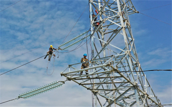 State Grid employees undertake maintenance work on a tower in Taizhou, Zhejiang province, in April. [WANG HUABIN/FOR CHINA DAILY]