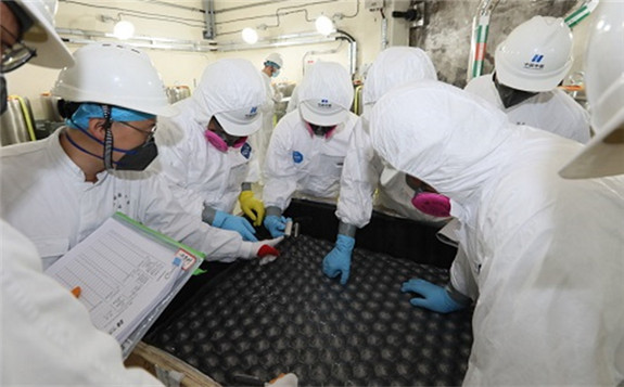 Workers load the first fuel elements into the HTR-PM (Image: China Huaneng)