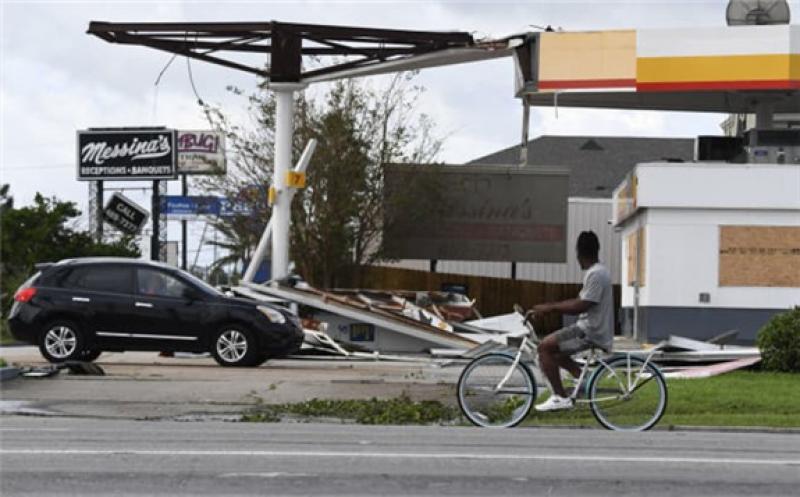 A person on a bicycle passes a damaged Shell station in Kenner, Louisiana, on August 30, 2021 after Hurricane Ida made landfall. Patrick T. Fallon | AFP | Getty Images