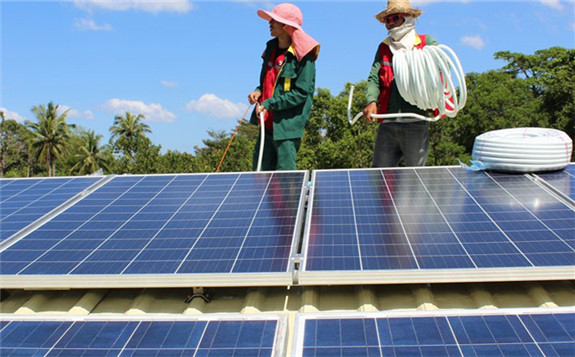 Technicians install photovoltaic panels on a house in a remote village. Solar Green Energy (Cambodia)