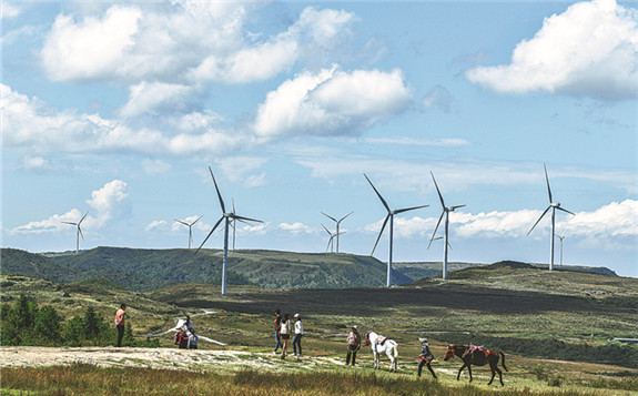 Tourists stroll near a wind power plant in Longli county, Guizhou province. [Photo/Xinhua]