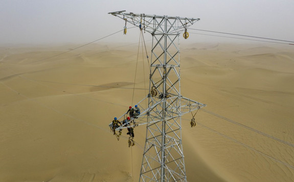 Aerial photo taken on Sept. 28, 2020 shows people working on a pylon at the Taklimakan Desert in Hotan Prefecture, northwest China's Xinjiang Uygur Autonomous Region. [Photo/Xinhua]